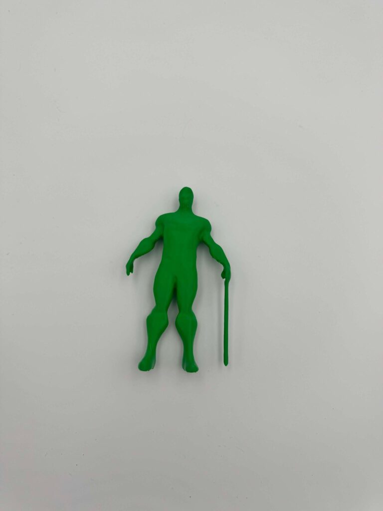 An image of a green 3D-printed human-like figure. The figure has a minimalist design with smooth surfaces, standing upright with a straight posture. It holds a long stick or cane in one hand, giving it a unique and purposeful appearance. The model's features are abstract, with no detailed facial or clothing elements, emphasizing its simplistic yet striking form.