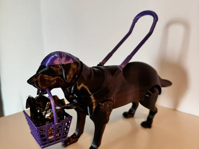 The model is a guide dog figure built from separate parts. The body has four legs, a tail and a round neck socket for the head. The head is a smooth dog head with floppy ears and a muzzle. The basket and handle form the guide-dog harness accessories.