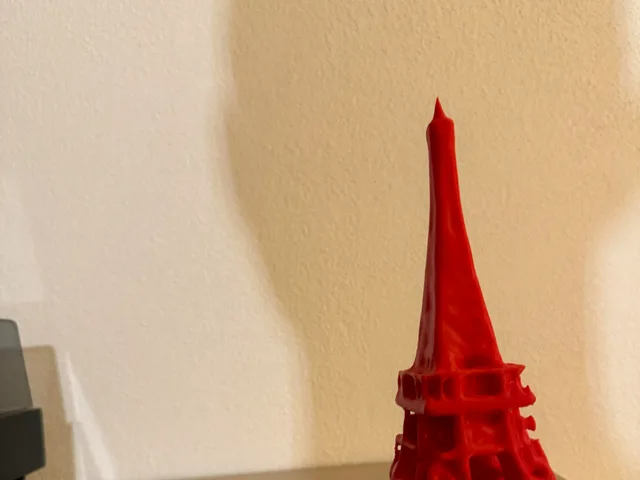 The model stands on a square base. The tower rises from four arched supports, narrows through the middle and ends in a slim pointed top. The surface has a rough, faceted texture rather than clean open latticework.