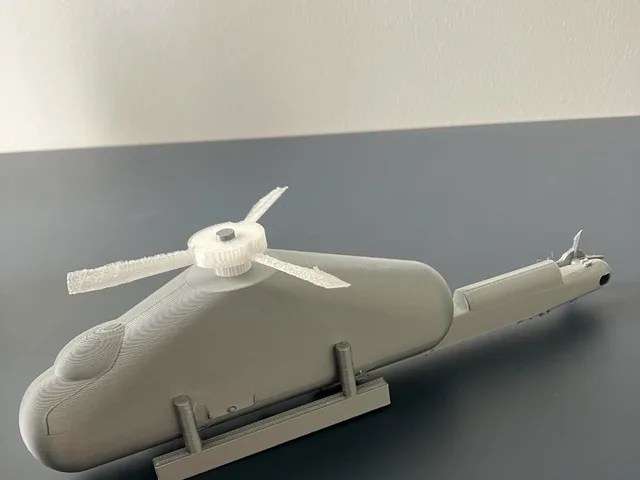 The body has a rounded cockpit at the front, a long tail boom at the back, landing skids underneath and a vertical post on top where a rotor could sit. The shape is smooth and simplified, with the helicopter silhouette doing most of the work.