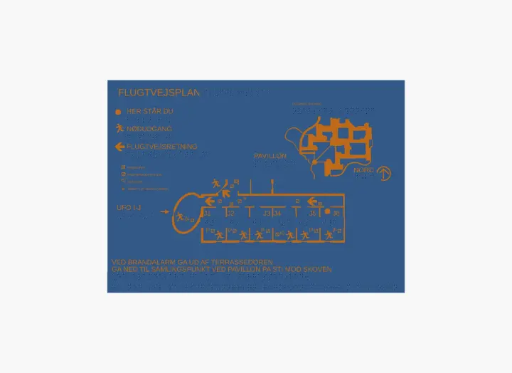 A flat top view shows a tactile emergency evacuation plan on a blue plate, with raised orange graphics, Braille labels, tactile routes, room labels, exit symbols, a north arrow and Danish instruction text.